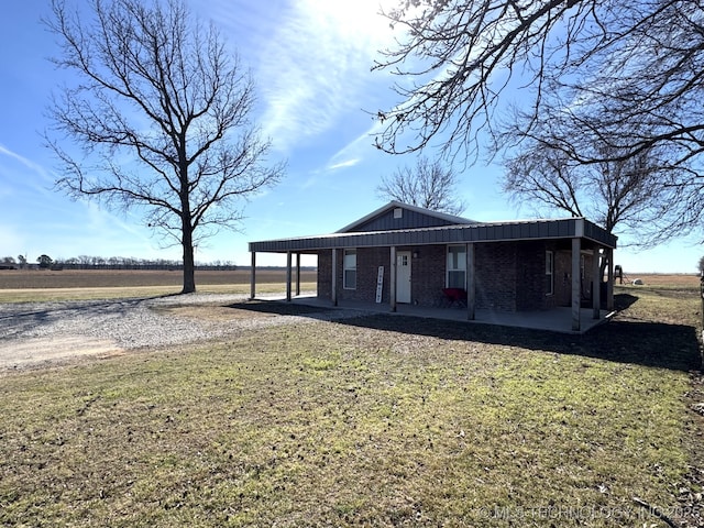 view of front of house with board and batten siding, a front yard, brick siding, and dirt driveway