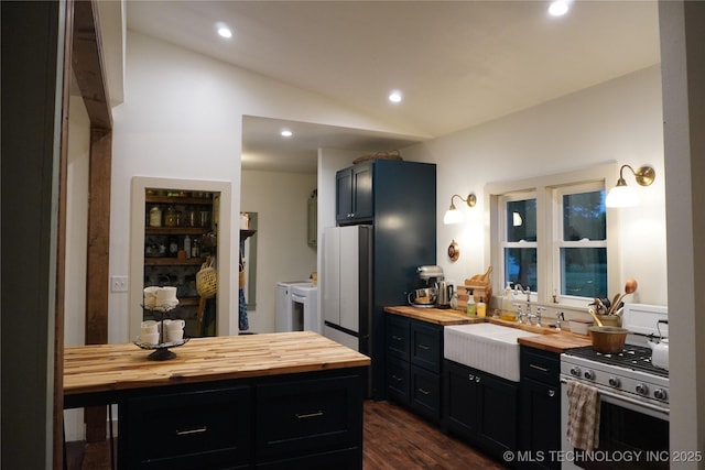 kitchen featuring washing machine and dryer, sink, butcher block counters, and stainless steel gas range