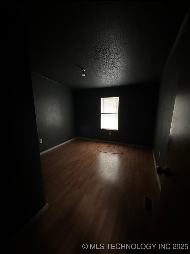 unfurnished room with wood-type flooring and a textured ceiling