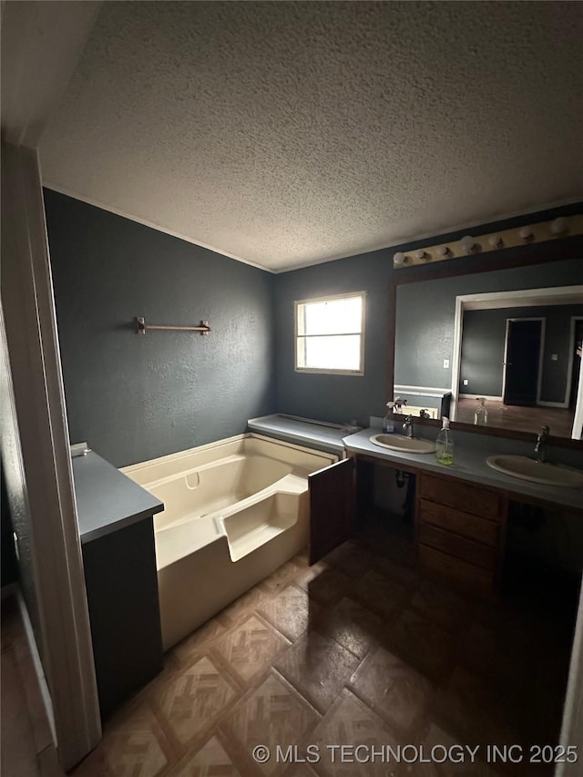 bathroom featuring a textured ceiling, vanity, and a bath