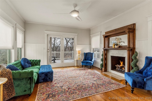 7637 S 26th W Ave, Tulsa, OK 74037 - living area featuring a ceiling fan, a fireplace with flush hearth, wood finished floors, wainscoting, and ornamental molding