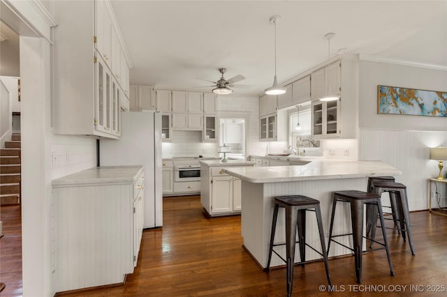 7637 S 26th W Ave, Tulsa, OK 74037 - kitchen with a peninsula, a kitchen breakfast bar, a ceiling fan, white cabinetry, and light countertops