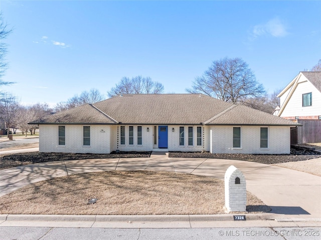 single story home featuring driveway, a shingled roof, fence, and brick siding