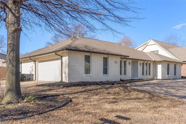 ranch-style home featuring a garage, concrete driveway, brick siding, and a shingled roof