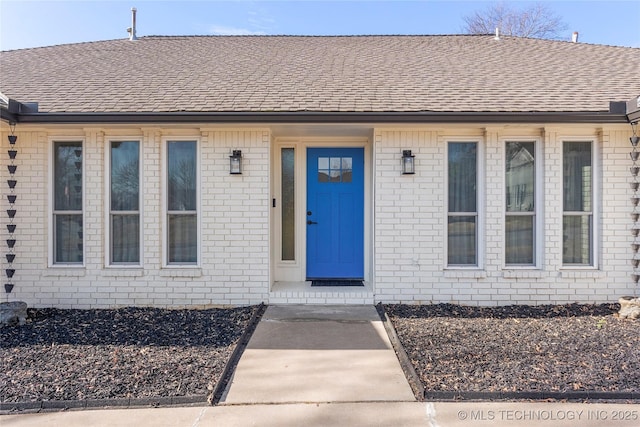 entrance to property with brick siding and roof with shingles