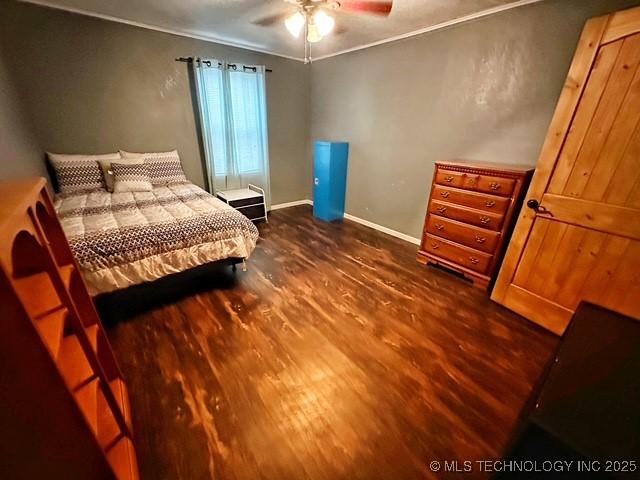 bedroom with baseboards, dark wood finished floors, and crown molding