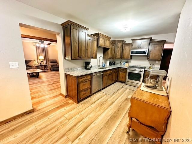 kitchen with baseboards, appliances with stainless steel finishes, dark brown cabinets, light wood-type flooring, and a sink