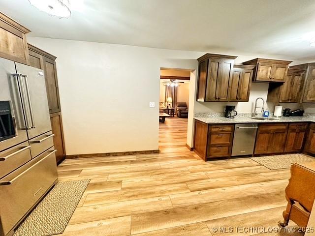 kitchen with dishwasher, light countertops, a sink, and light wood-style floors