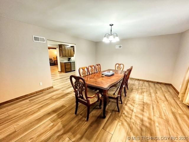 dining area with a chandelier, visible vents, and light wood-style floors