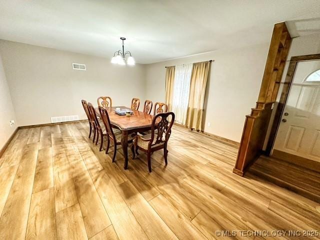 dining room featuring light wood finished floors, visible vents, and a chandelier