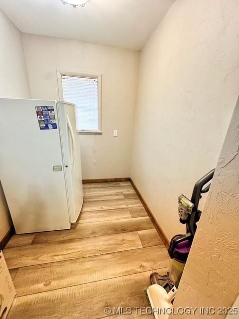 kitchen with light wood-style floors, freestanding refrigerator, light countertops, and baseboards