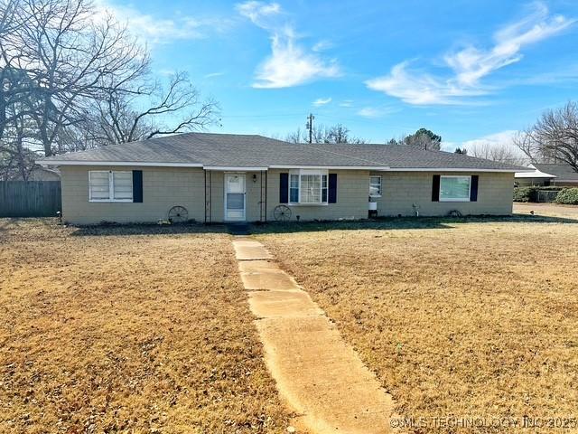 ranch-style home with a front yard and fence