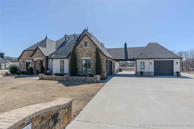 french provincial home featuring driveway, stone siding, and an attached garage