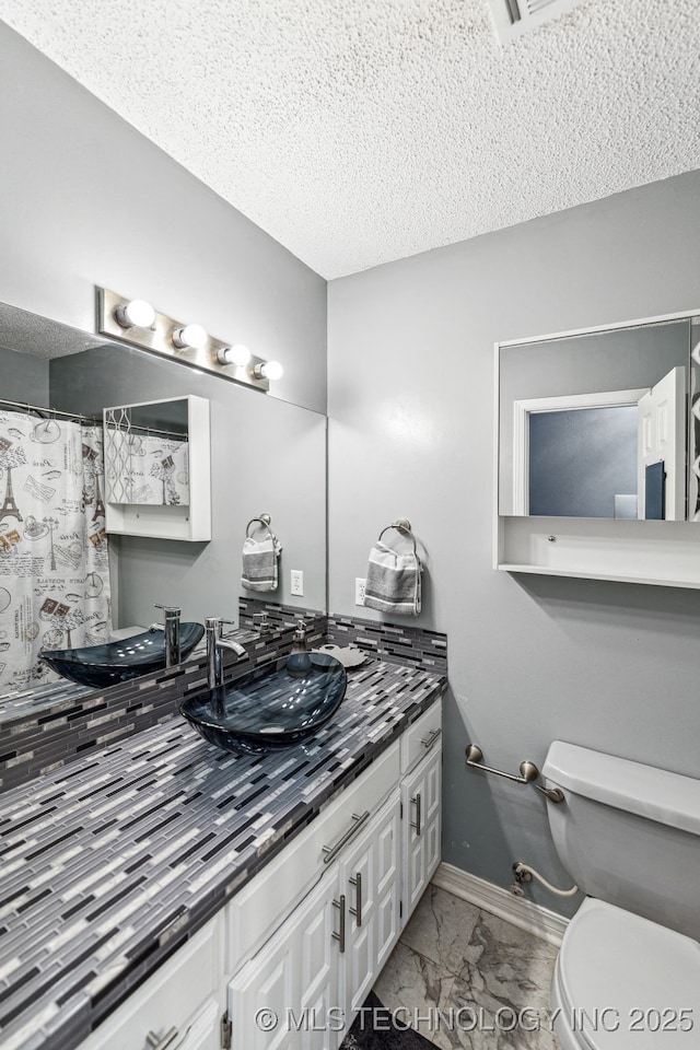 bathroom featuring vanity, toilet, and a textured ceiling