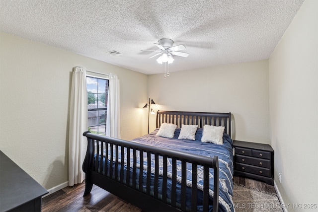 bedroom with a textured ceiling, ceiling fan, and dark hardwood / wood-style floors