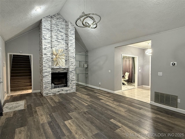 unfurnished living room with hardwood / wood-style flooring, a stone fireplace, and a textured ceiling