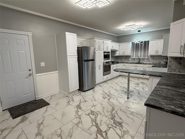 kitchen with sink, stainless steel fridge, white cabinets, hanging light fixtures, and ornamental molding