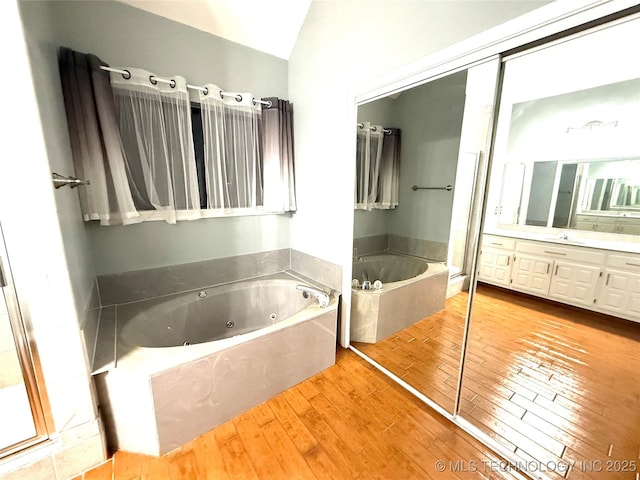 bathroom featuring hardwood / wood-style flooring, vanity, vaulted ceiling, and a bathtub