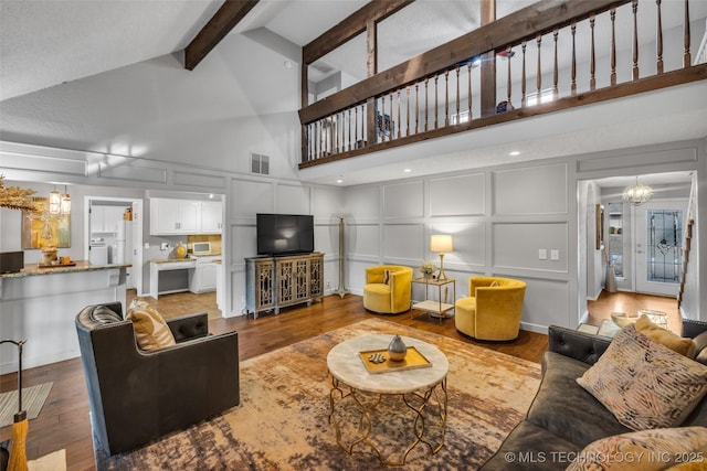 living room featuring a decorative wall, beamed ceiling, and wood finished floors