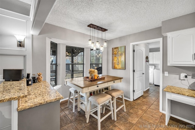 dining area featuring washing machine and dryer, baseboards, and a textured ceiling