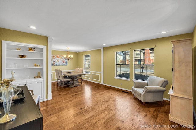 living area featuring baseboards, recessed lighting, wood finished floors, and an inviting chandelier