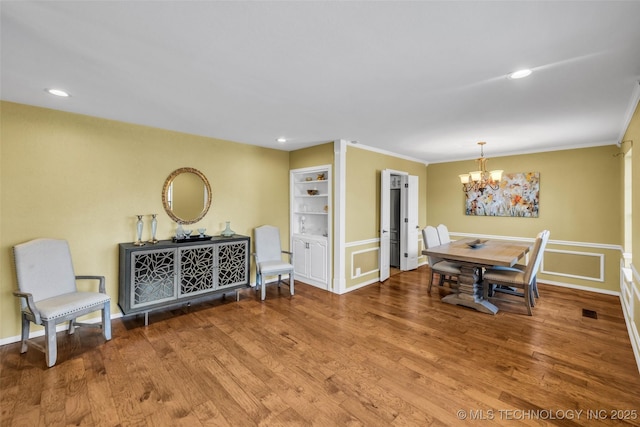 dining space featuring recessed lighting, an inviting chandelier, wood finished floors, and crown molding