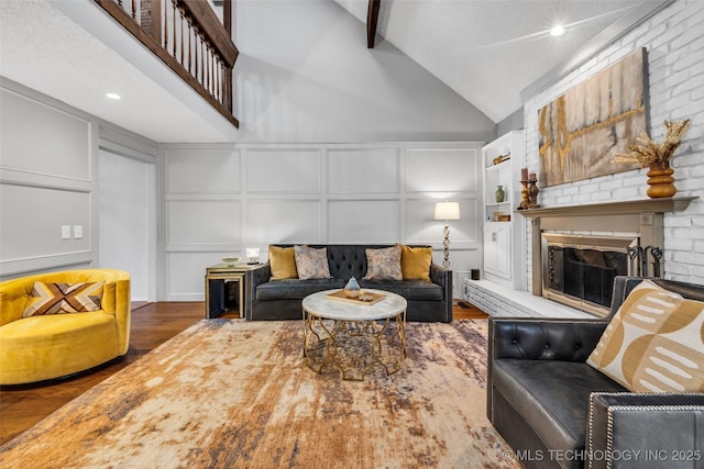 living area featuring high vaulted ceiling, a decorative wall, a brick fireplace, beam ceiling, and dark wood finished floors