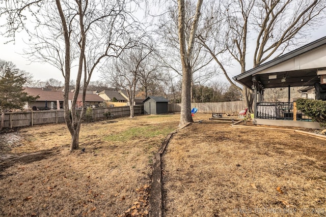 view of yard featuring a fenced backyard, a residential view, a deck, an outdoor structure, and a shed