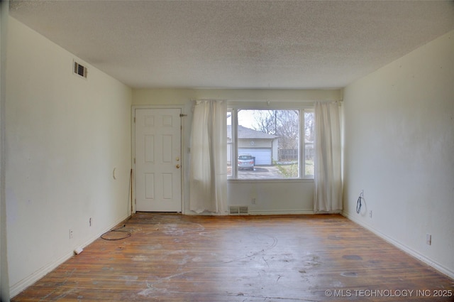 empty room with hardwood / wood-style flooring and a textured ceiling