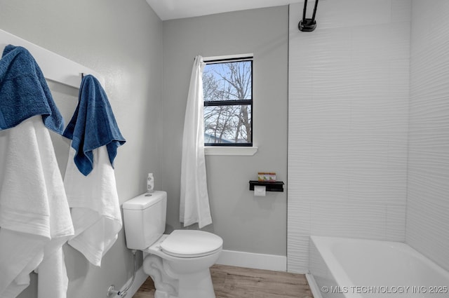 bathroom featuring hardwood / wood-style floors, a tub to relax in, and toilet