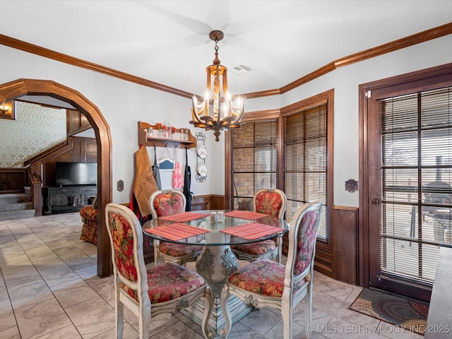 dining space featuring a chandelier, crown molding, and wood walls