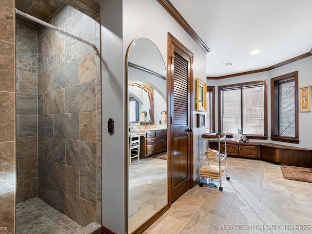 bathroom with tiled shower and ornamental molding