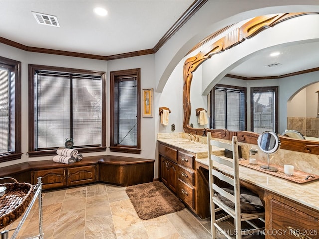 bathroom with a healthy amount of sunlight, vanity, and ornamental molding