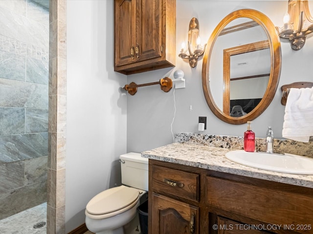 bathroom with vanity, a tile shower, and toilet