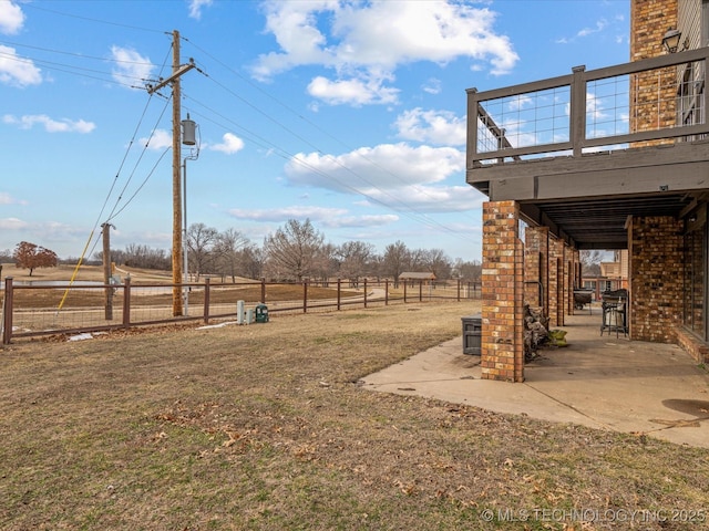 view of yard with a deck, a rural view, and a patio