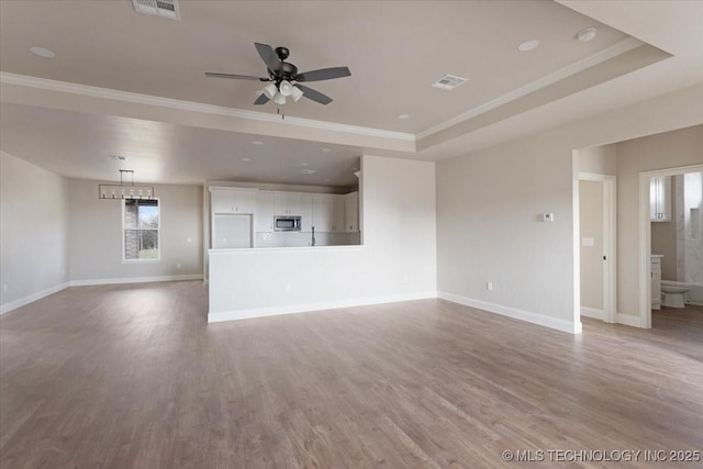 unfurnished living room featuring crown molding, a raised ceiling, and hardwood / wood-style floors