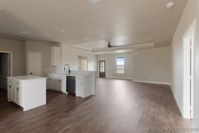 kitchen with stainless steel dishwasher, sink, white cabinets, and a tray ceiling