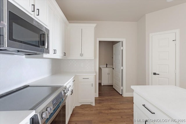 kitchen with white cabinets, stainless steel appliances, dark hardwood / wood-style flooring, and tasteful backsplash