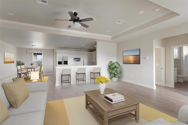 living room with a tray ceiling, ceiling fan, crown molding, and light hardwood / wood-style floors