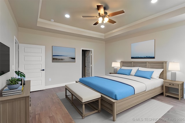 bedroom with wood-type flooring, a tray ceiling, and ornamental molding