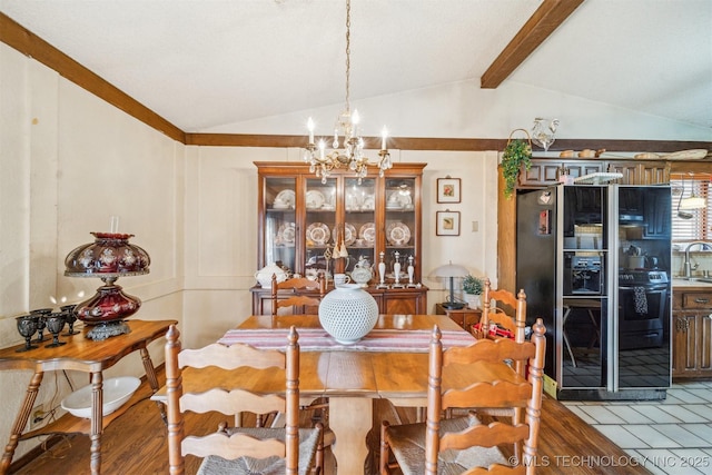 dining area with sink, hardwood / wood-style floors, vaulted ceiling with beams, and a chandelier