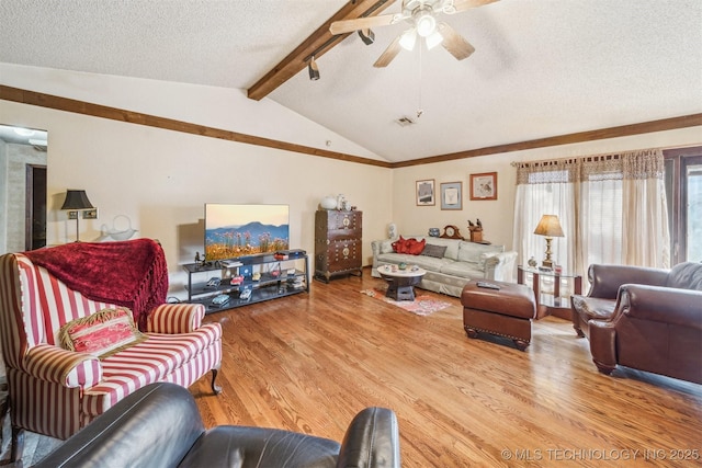 living room featuring ceiling fan, lofted ceiling with beams, wood-type flooring, and a textured ceiling