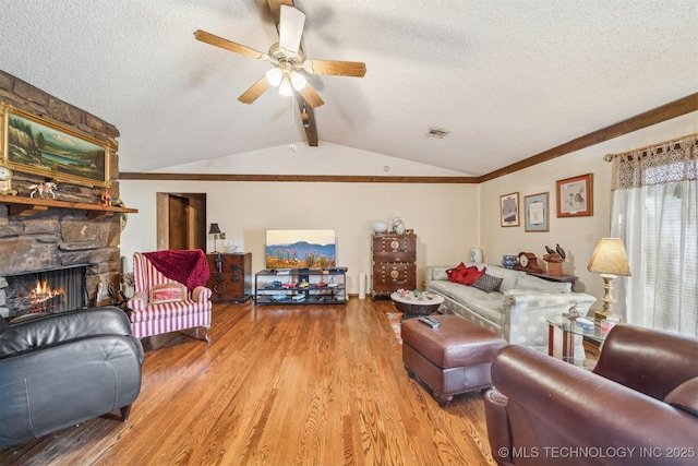 living room featuring a fireplace, light hardwood / wood-style flooring, lofted ceiling with beams, and a textured ceiling