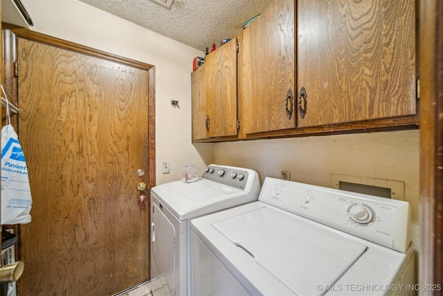 clothes washing area featuring washer and dryer, cabinets, and a textured ceiling