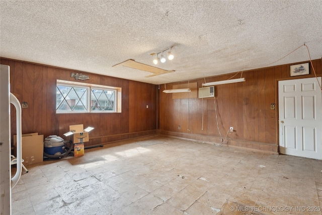 interior space featuring a textured ceiling, a wall mounted air conditioner, and wooden walls