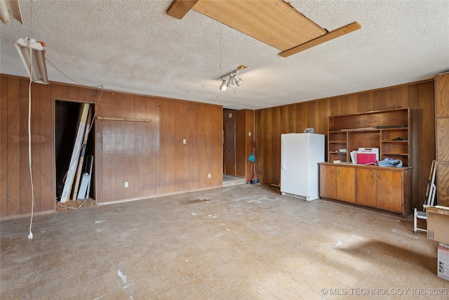 interior space featuring a textured ceiling and wooden walls