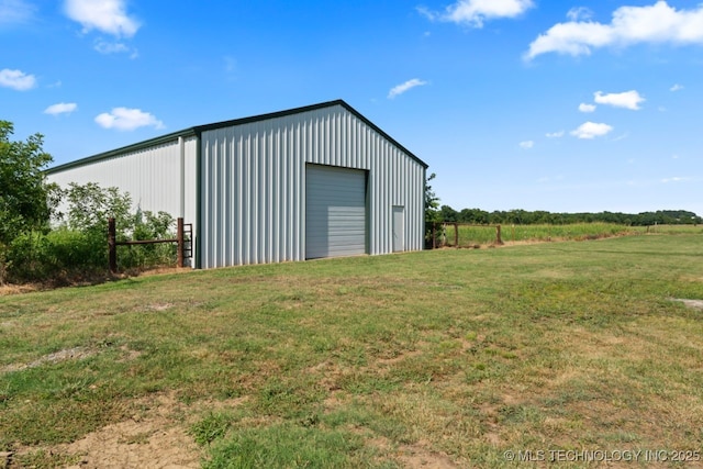 view of outdoor structure with a lawn, a garage, and a rural view