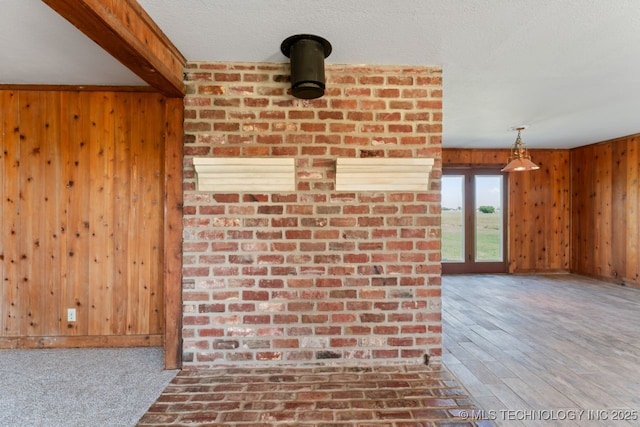 interior space featuring hardwood / wood-style flooring, wood walls, a textured ceiling, and beam ceiling