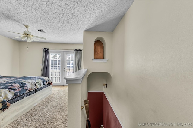 carpeted bedroom featuring a textured ceiling, ceiling fan, visible vents, access to exterior, and french doors