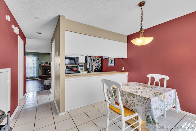 dining space with a textured ceiling, baseboards, and light tile patterned floors